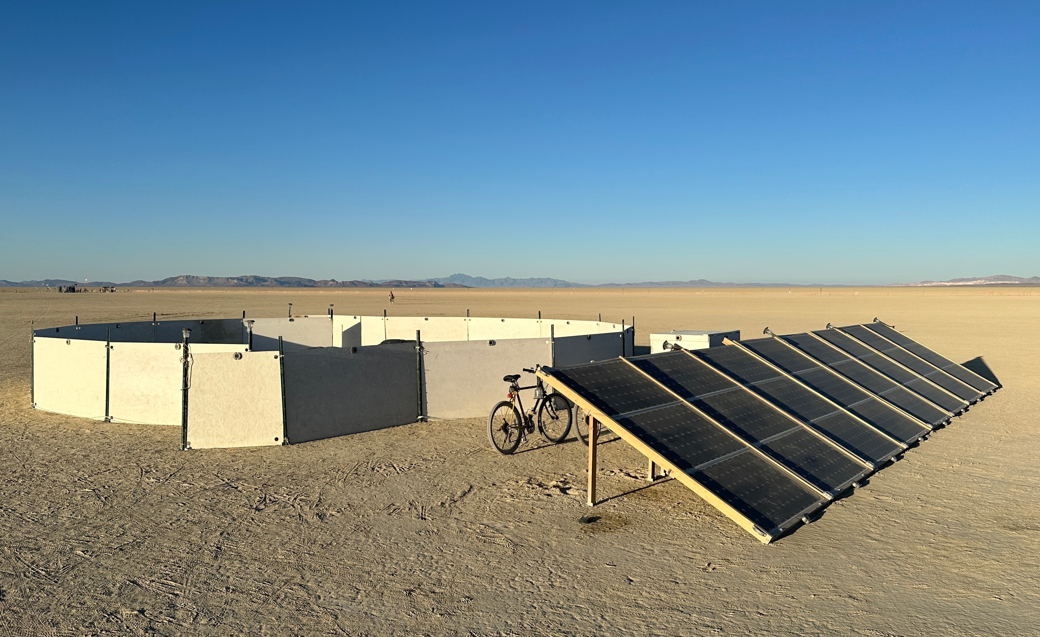 a circular sound installation in the desert with a large bank of prominent solar panels, in bright daylight