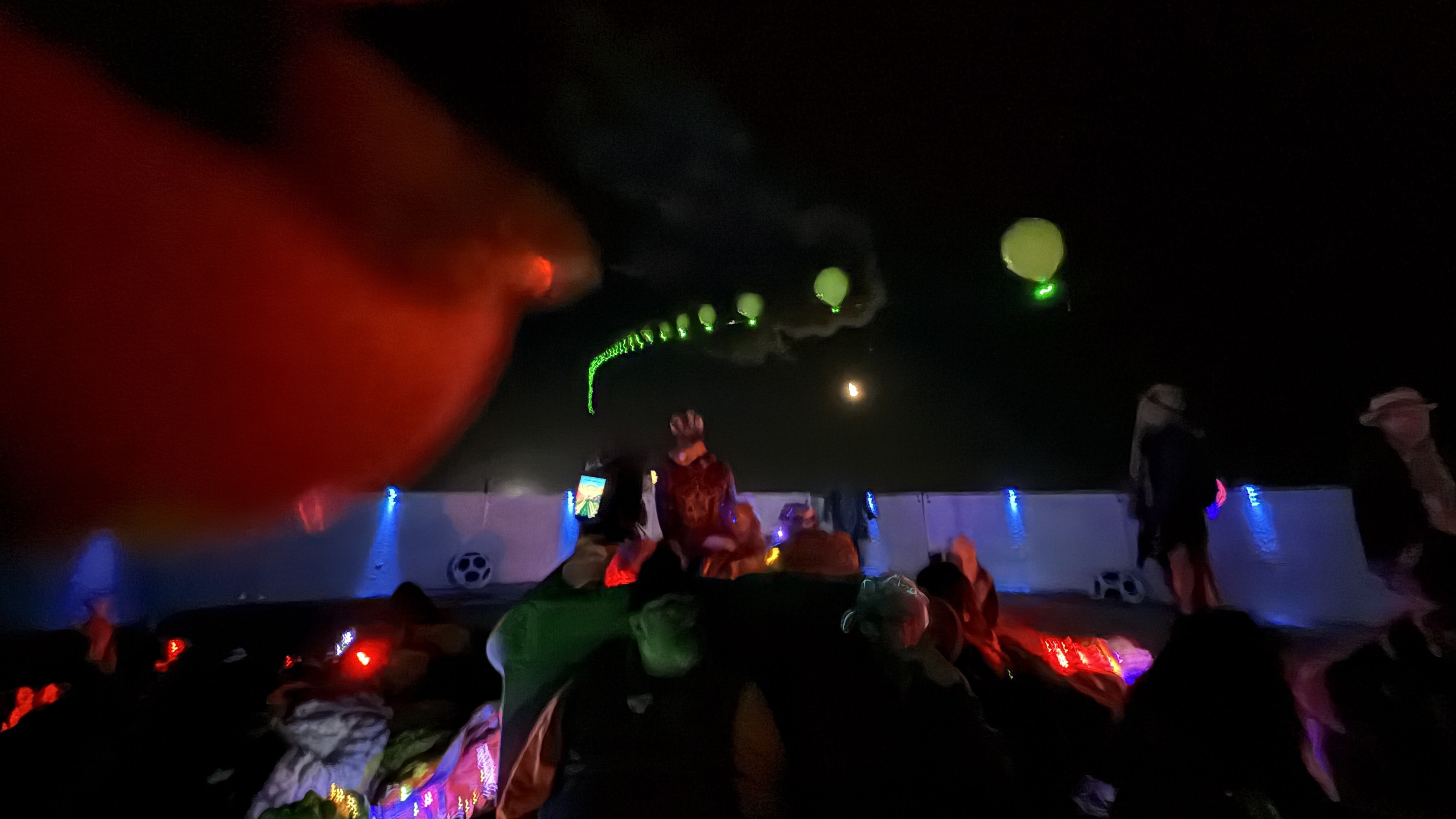 the interior of a circular sound installation in the desert at night, with a chain of glowing balloons growing out of it