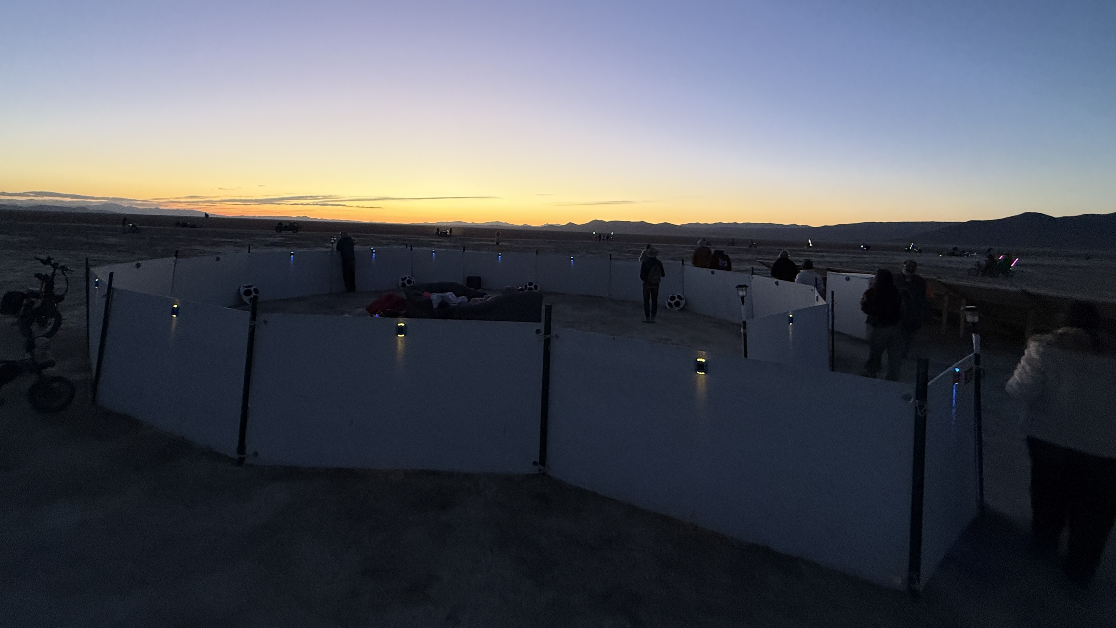 a circular sound installation in the desert just before dawn, with solar lights still barely shining